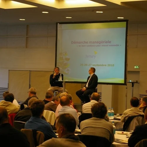 Dos ponentes en una conferencia sobre consultoría de liderazgo sentados frente al público